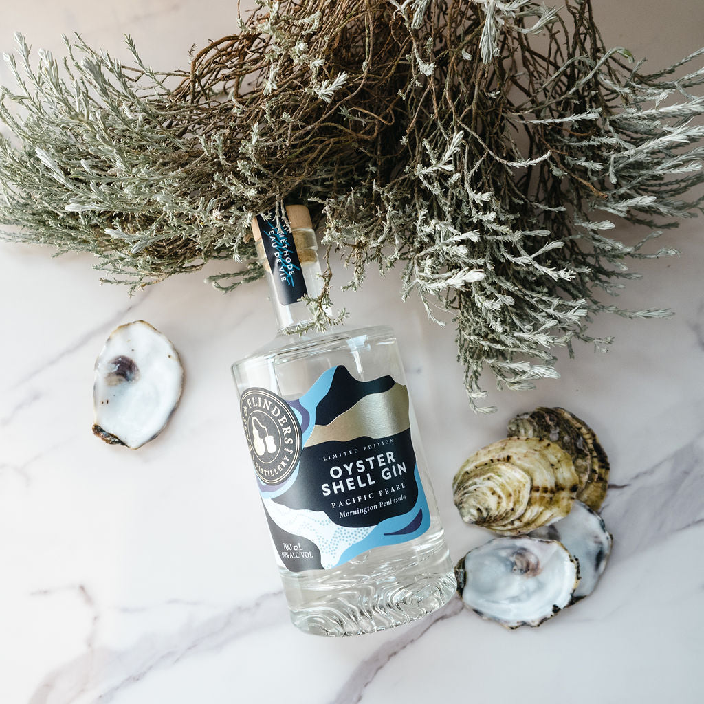 Bass & Flinders Distillery oyster shell gin in bottle surrounded by scattered empty oyster shells and coastal saltbush