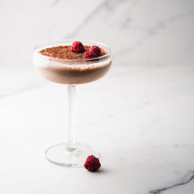Bass & Flinders Lamington gin cocktail in a glass with raspberries and chocolate garnish on a white background