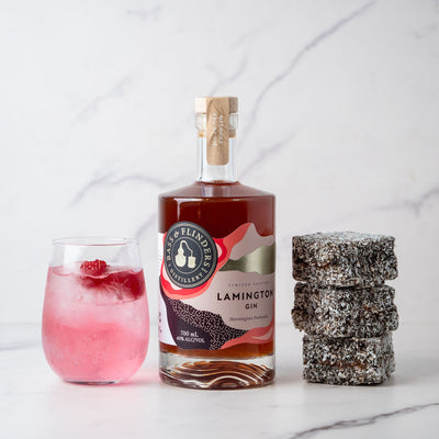 Bottle of Bass & Flinders Lamington Gin with a spritz cocktail in glass and lamingtons on a marble surface