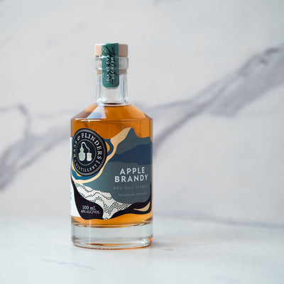 Bottle of bass & flinders distillery Apple Brandy with a label on a white marble background