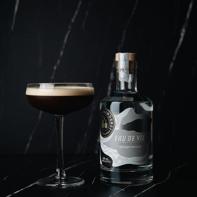 Bottle of Bass & Flinders Distillery Eau de Vie with an espresso martini cocktail in a 
 glass on a dark background