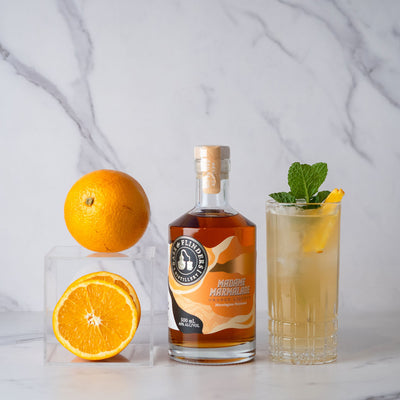 Bottle of bass & flinders distillery Madame Marmalade liqueur with oranges and a madams mule cocktail on a marble surface