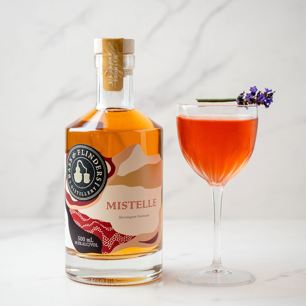 Bottle of bass and flinders distillery Mistelle with a fancy Mistelle cocktail on a white background