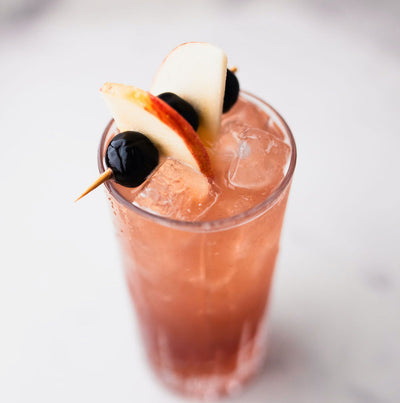Bass & Flinders Distillery Rain in the Orchard apple brandy Cocktail with apple and cherry garnish on a white background